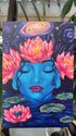 A hand holds up a postcard depicting artwork of the goddess Gaia, whose head is adorned with three large pink lotuses. She is surrounded by lilypads and a lotus that contains the planet Earth. Above her head, a galaxy swirls.