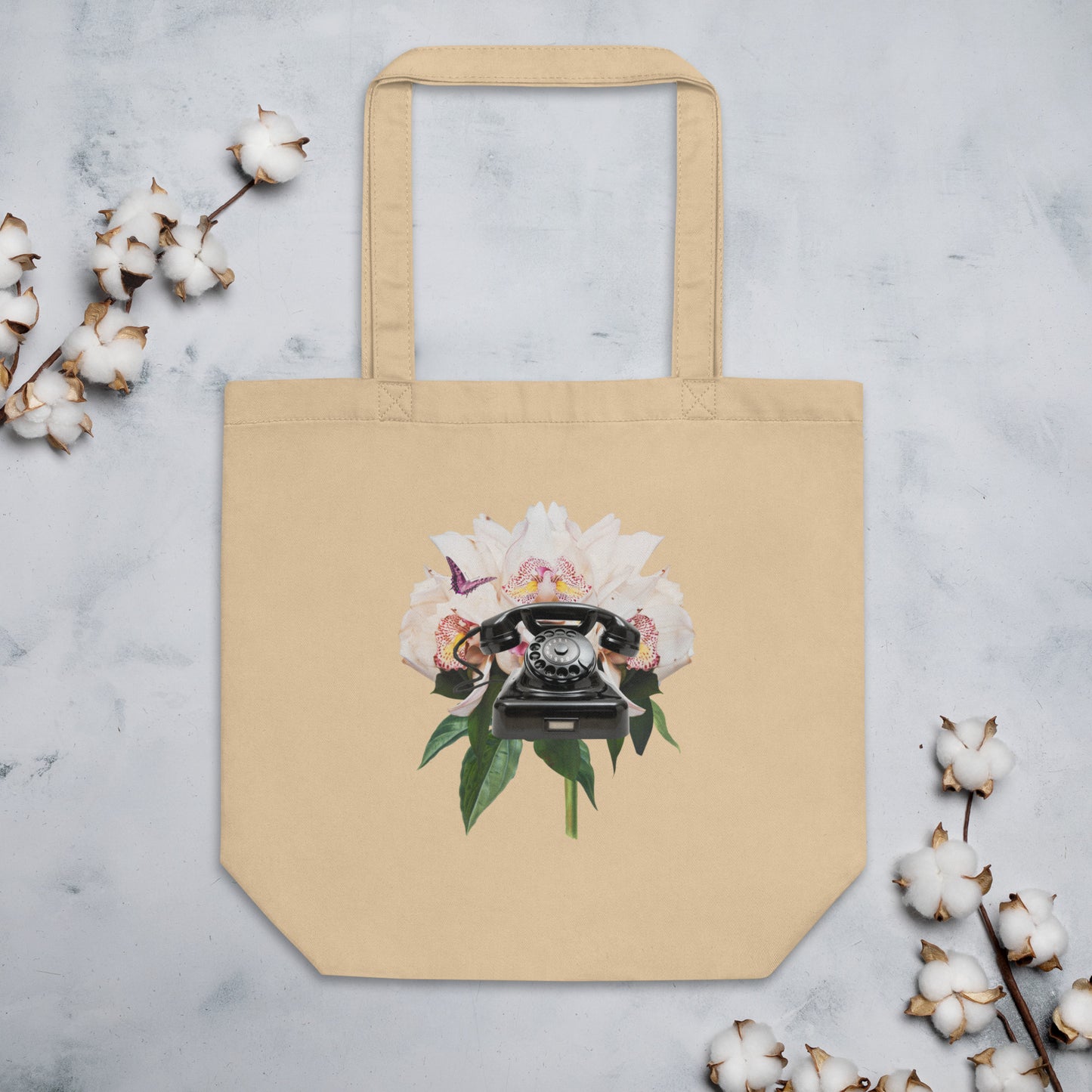 A tan tote bag showcasing a design of a black rotary telephone set against a background of large, blooming white peonies with green leaves.