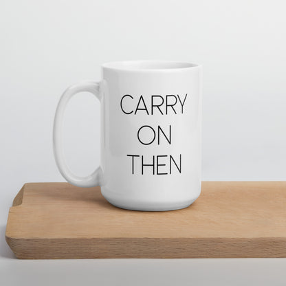 A glossy white ceramic mug with thin black all-caps text that reads 'CARRY ON THEN', positioned on a wooden cutting board against a neutral background.