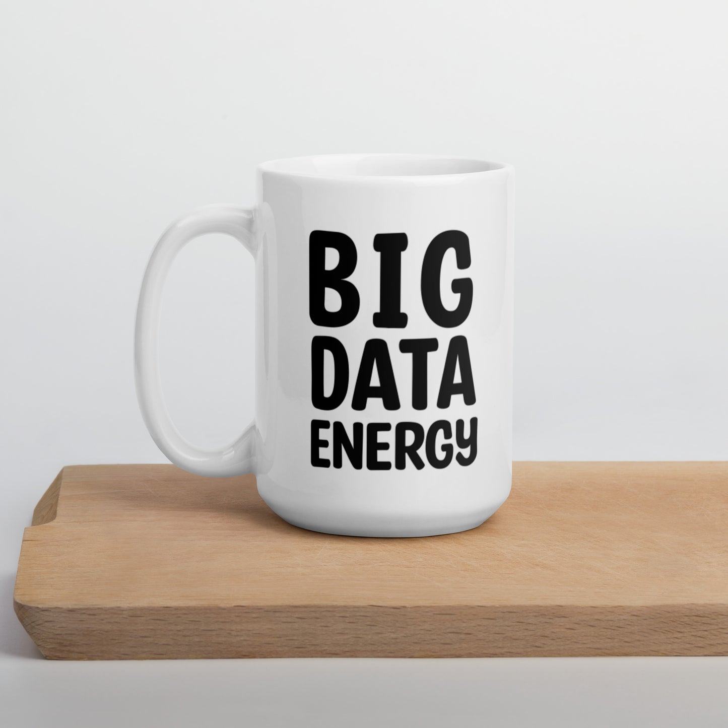 A glossy white ceramic mug with bolded black bubble text that reads 'BIG DATA ENERGY', positioned on a wooden cutting board against a neutral background.